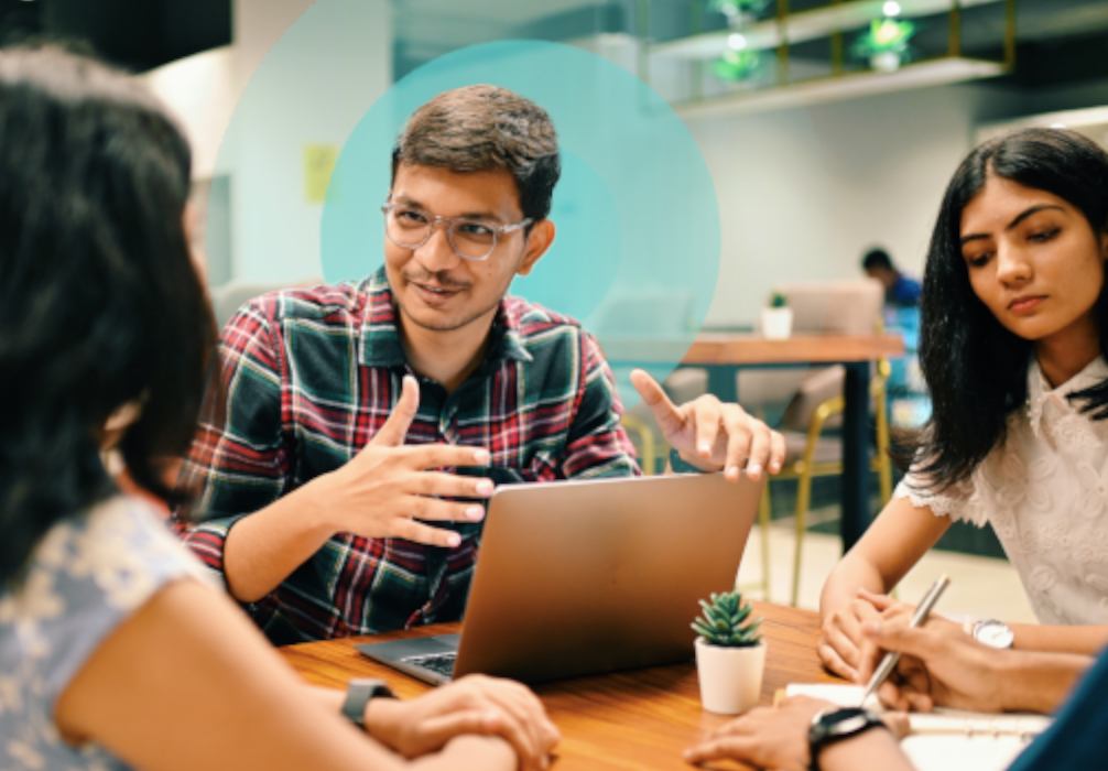 Group of young professionals engaged in discussion around a laptop